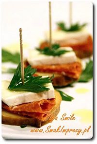 Puff pastry canapés topped with cheese and fresh parsley, arranged on a white platter with toothpicks.
