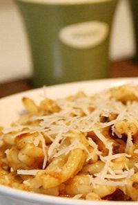 Plate of pasta with mushrooms and melted cheese on top, creamy sauce visible; green cup blurred in the background.