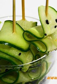 Cucumber ribbons curled on wooden skewers inserted into a glass as a fresh garnish.