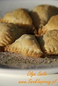 Golden-brown triangular pastries with crimped edges cooling on a baking sheet.