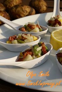 Several white ceramic spoons filled with colorful chopped salads, arranged on a white platter with a lemon half in the background.