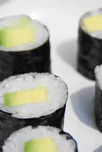 Close-up of maki sushi rolls with white rice, nori, and yellow pickled radish filling on a white background.