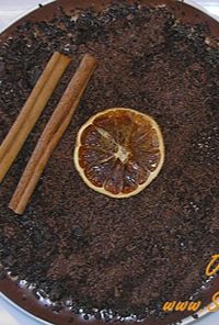 Chocolate cake topped with an orange slice and two cinnamon sticks as garnish.